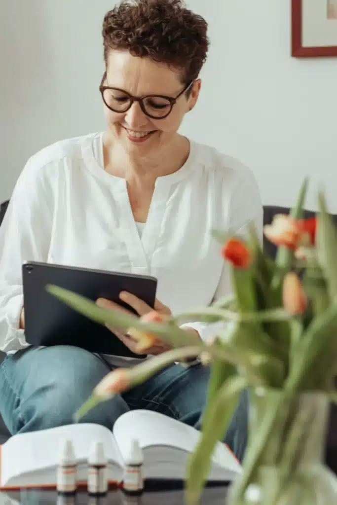 Silke Lemhöfer, Hormoncoach, liest auf dem Sofa, davor Tulpen
