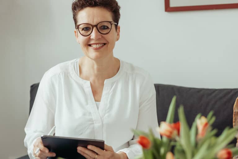 Silke Lemhöfer mit Tablet auf dem Sofa ihrer Onlinepraxis