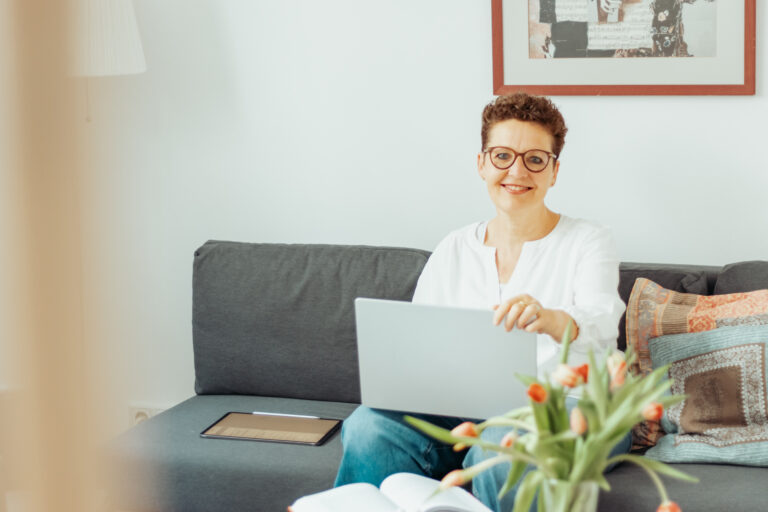 Silke Lemhöfer mit Laptop auf dem Sofa ihrer Onlinepraxis