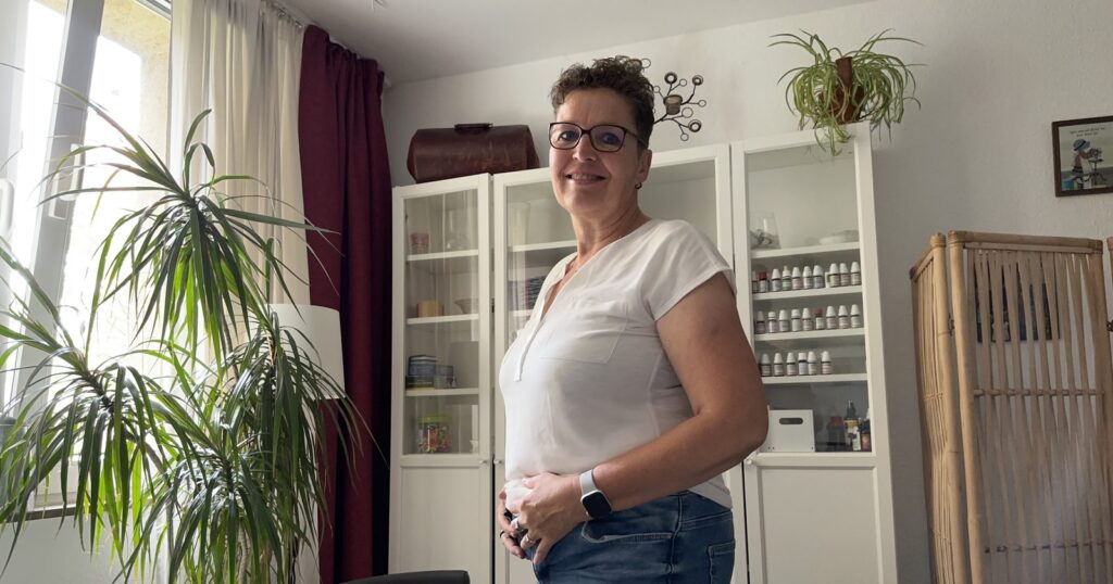 Silke Lemhöfer, Heilpraktikerin, mit den Händen am Bauch in ihrem Behandlungsraum