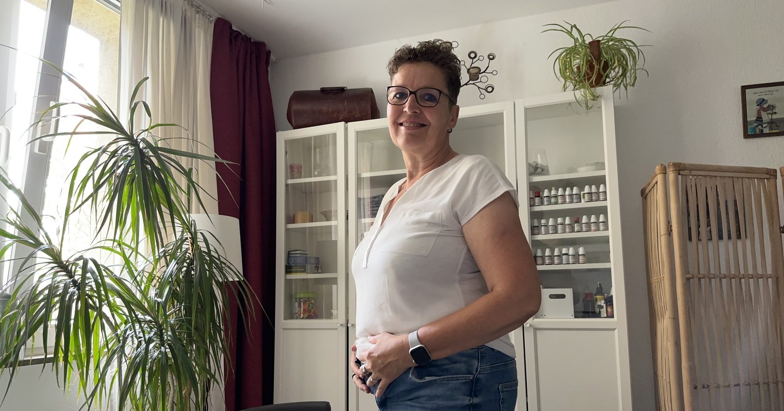 Silke Lemhöfer, Heilpraktikerin, mit den Händen am Bauch in ihrem Behandlungsraum