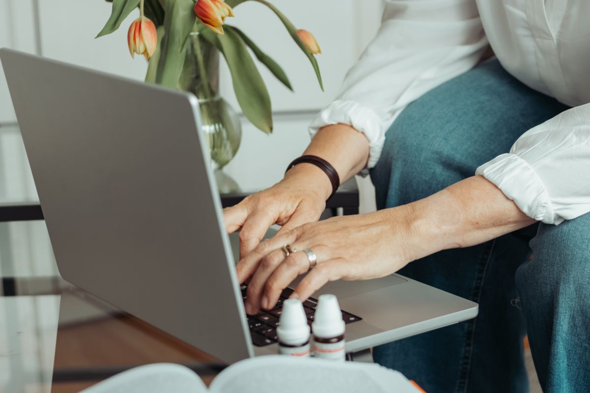 Silkes Hände am Laptop, davor zwei Fläschchen mit homöopathischen Mitteln