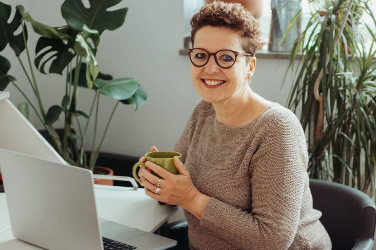 Silke Lemhöfer am Schreibtisch mit Laptop und Teetasse, lächelnd